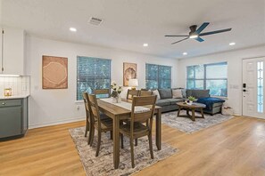 A modern living room with a dining area, a sofa, and a ceiling fan. - Stagecoach Breeze | Lake View•Firepit•Pet Friendly (Canyon Lake)