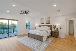 A bedroom with a bed, a ceiling fan, a nightstand, and a view through a sliding glass door. - Stagecoach Breeze | Lake View•Firepit•Pet Friendly (Canyon Lake)