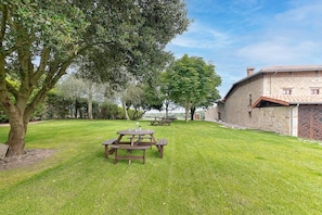 A grassy outdoor area with picnic tables and a stone building. - InfinityCoast V byFidalsa (Piélagos)