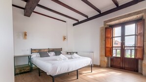 Ein Schlafzimmer mit einem Bett, Nachttischen, einem Heizkörper und einer Holztür mit Fenstern.