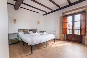 A bedroom with a bed, bedside tables, a radiator, and a wooden door with windows. - InfinityCoast V byFidalsa (Piélagos)
