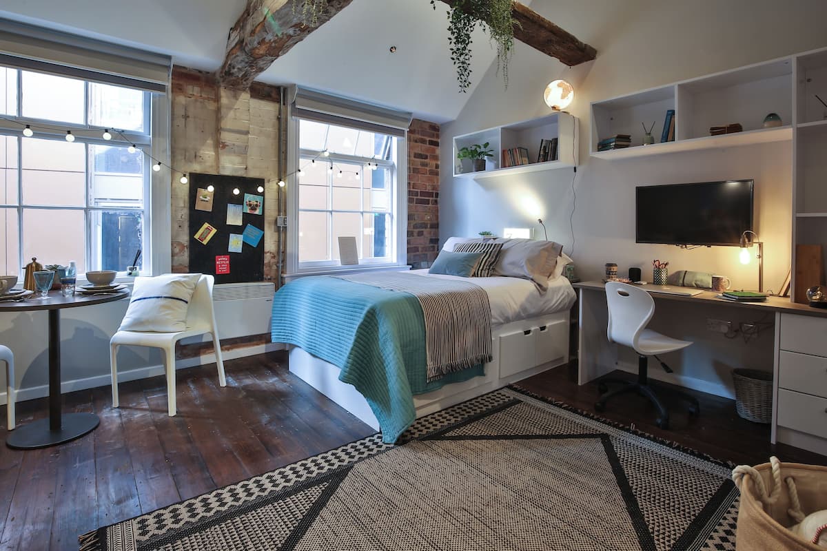 Un dormitorio con cama, escritorio, silla y un amplio ventanal.