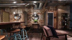 Un coin bar au style rustique, avec des tabourets en bois, un comptoir et un espace salon agrémenté d’un banc à motifs.