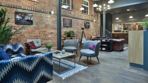 Un vaste espace salon agrémenté d’un mur en briques, de meubles modernes et d’une variété de sièges.