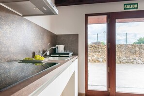 A kitchen with a modern design, a sink, a dish rack, and a view of the outside through a glass door.