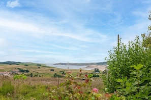 A landscape view with a body of water, rolling hills, and a distant town.