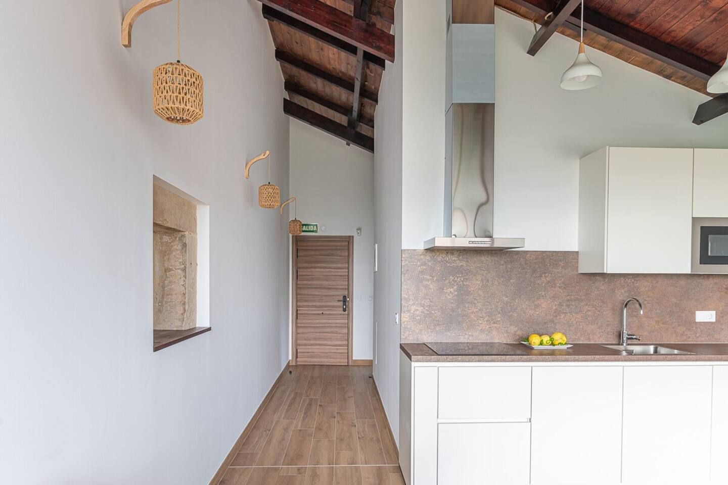 A modern kitchen with a wooden ceiling, a built-in oven, and a sink.