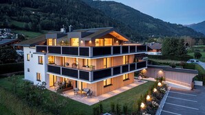 A modern multi-story building with a flat roof, large windows, and a balcony.