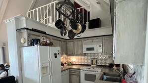 A kitchen with white appliances, a microwave, and a red container on the counter.