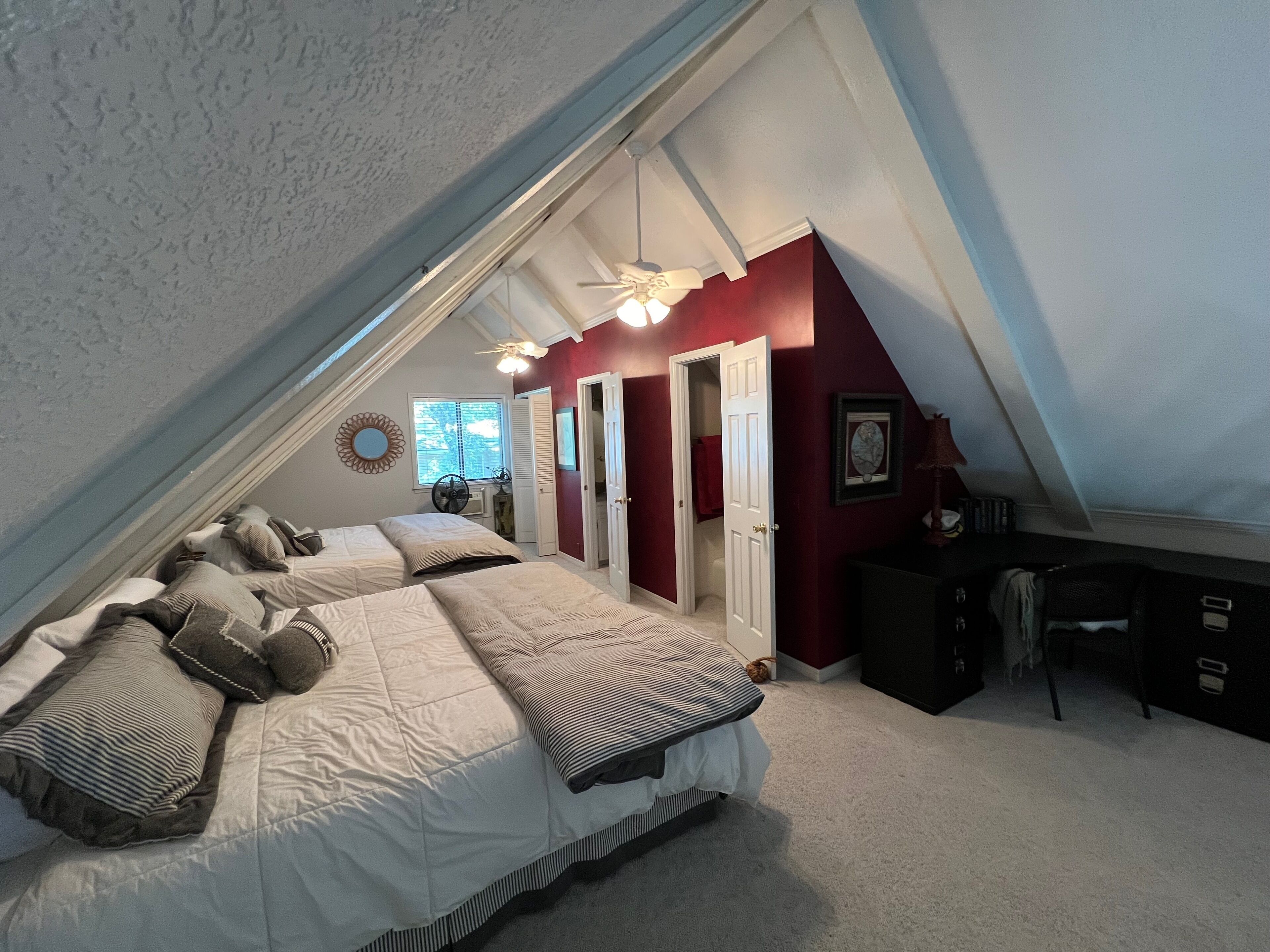 A bedroom with two beds, a ceiling fan, and a window.