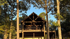 A wooden cabin with a balcony, surrounded by trees.