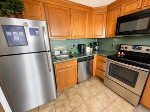 A kitchen with wooden cabinets, stainless steel appliances, and a green countertop.
