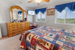 A bedroom with a large bed, a wooden dresser, a mirror, a television, and a window with blue curtains. - ML178 Great Views & Location EZ Parking  Next To Village (Snowshoe)