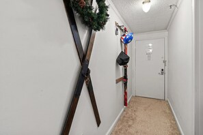 A hallway with skis and a snowboard leaning against the wall, a door at the end, and a small Christmas wreath. - ML178 Great Views & Location EZ Parking  Next To Village (Snowshoe)