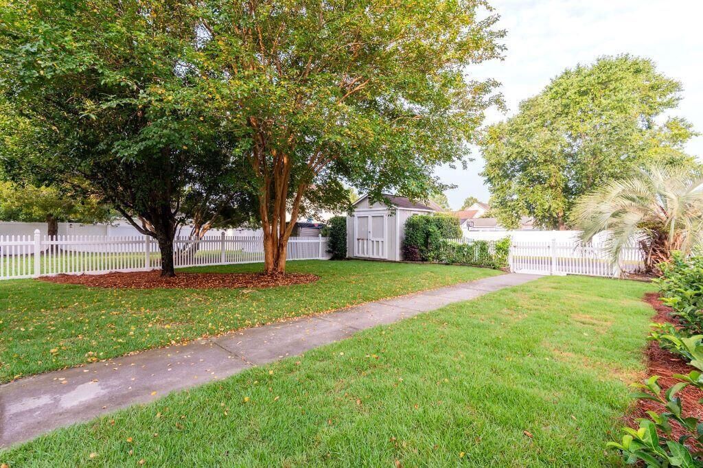 A residential property with a well-maintained lawn, a pathway, and a white picket fence.
