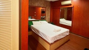 Una habitación de hotel con cama, espejo, armario y aire acondicionado instalado en la pared.