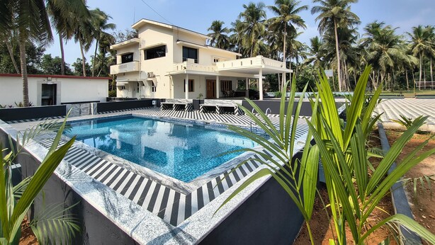 Un bâtiment moderne à deux étages doté d’une piscine, entouré de palmiers.