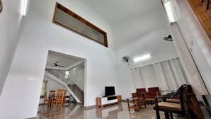 Un salon spacieux avec un escalier, un téléviseur et un grand miroir au mur.