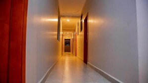A long, narrow hallway with doors on both sides and a tiled floor. - Entebbe Serenity breeze apartments - Single Room with Lake View (Entebbe)