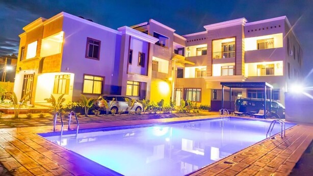 A modern multi-story hotel with a swimming pool, outdoor seating, and a covered area. - Entebbe Serenity breeze apartments - Single Room with Lake View (Entebbe)