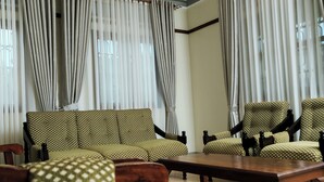 A room with a sofa and armchairs, a wooden coffee table, and sheer curtains. - Kandez Holiday Home (Entebbe)