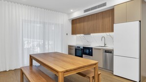 A modern kitchen with wooden cabinets, a marble countertop, and stainless steel appliances. - The Base at Abbott. Unwind with Private Spa -14 Abbott Street (Jindabyne)