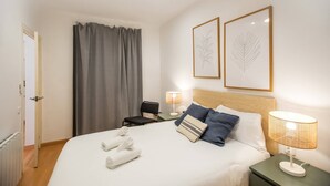 Une chambre d’hôtel avec un lit, deux tables de chevet, une lampe et une porte.