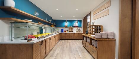 Une cuisine moderne avec des meubles en bois, un bar pour prendre le petit-déjeuner et un mur d’accent bleu.