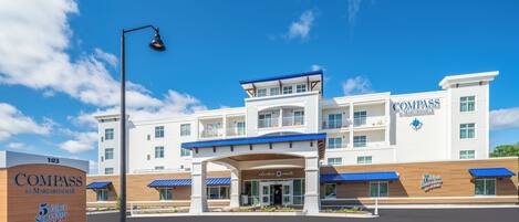 A multi-story hotel with a prominent entrance, a covered outdoor area, and signage for the Compass by Margaritaville brand.