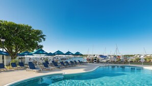 A clear blue pool with lounge chairs and umbrellas, surrounded by a white fence and boats in the background. - Compass by Margaritaville Beaufort (Beaufort)