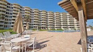 Ein Resort mit Poolbereich, Sitzgelegenheiten im Freien und einem großen Gebäude mit mehreren Balkonen.