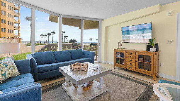 Ein Wohnzimmer mit einem blauen Sofa, einem Holztisch und einem Fernseher an der Wand.