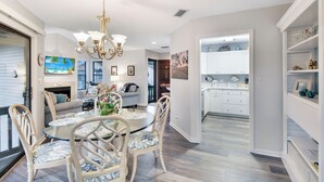 A spacious living room with a round glass table and chairs, a chandelier, and a fireplace. - Nice 3 bedroom condo located in Harbour Oaks (Saint Simons Island)