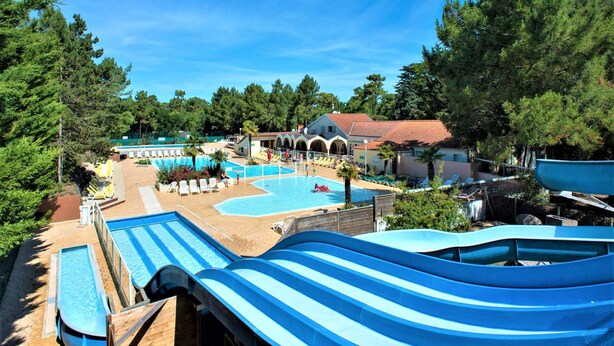 A resort with multiple swimming pools, a water slide, and a variety of lounge chairs.