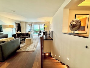 A modern living room with a sofa, coffee table, and a staircase leading to an upper level.