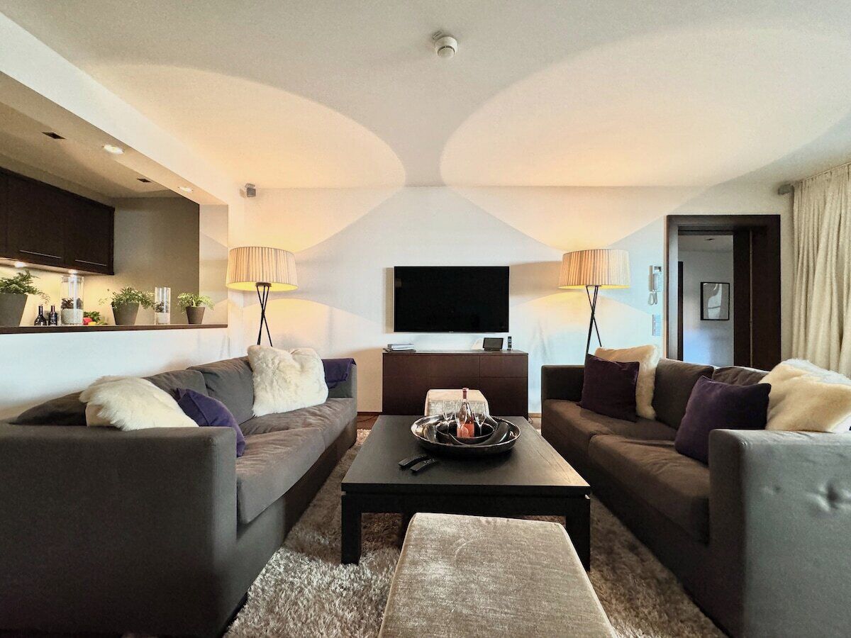 A modern living room with two sofas, a coffee table, and a flat-screen TV.