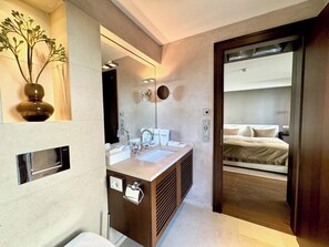 A modern bathroom with a built-in sink, mirror, and towel dispenser.
