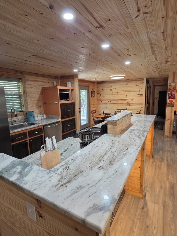 A kitchen with wooden walls, a marble countertop, and a built-in stove.