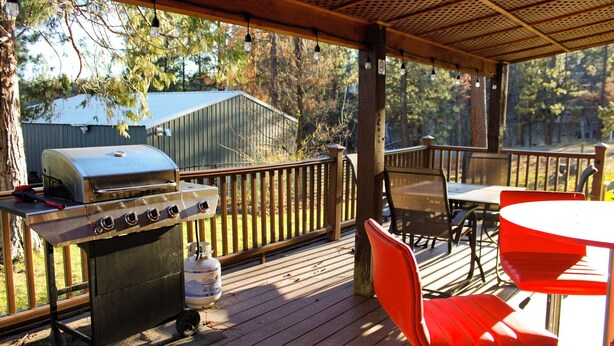 Une terrasse extérieure couverte, équipée d’un barbecue, de chaises et d’une table.