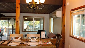 Un coin repas avec des meubles en bois, un lustre et une fenêtre équipée de stores.