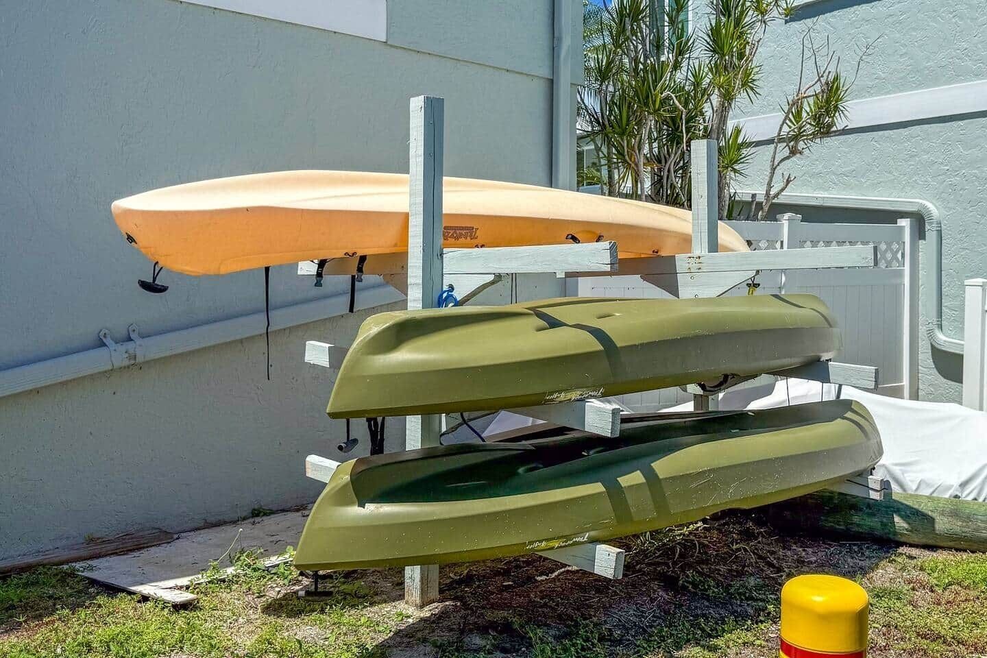 Un support à kayaks fixé au mur, portant deux kayaks, l’un orange et l’autre vert.