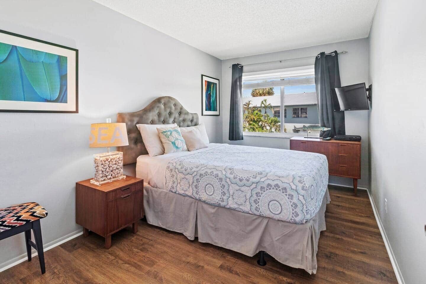 Une chambre à coucher avec un lit, une table de chevet et un téléviseur posé sur une commode.