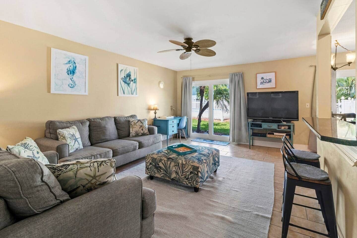 Ein Wohnzimmer mit Sofa, Ottoman, Fernseher und Deckenventilator.