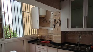 A kitchen with white cabinets, a black countertop, and a window with vertical blinds. - Luanda, Angola! Next to the Multipurpose Pavilhao! Centralidade do Kilamba, block M15 (Kilamba)