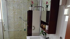 A bathroom with a glass shower enclosure, a white sink with a dark cabinet, and a mirror with a wooden frame. - Luanda, Angola! Next to the Multipurpose Pavilhao! Centralidade do Kilamba, block M15 (Kilamba)