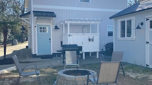 Een tweelaags huis met een patio, voorzien van een vuurkorf van steen, buitenmeubilair en een pergola.