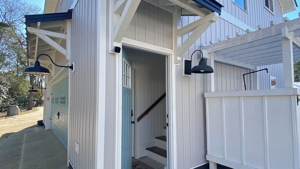 Een huis met twee verdiepingen, een veranda, een zichtbare trap en een garage.