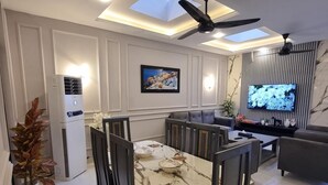 Un espace repas moderne avec une table en marbre, des chaises foncées, un ventilateur de plafond et un téléviseur fixé au mur.