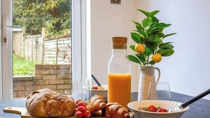 A breakfast setting with bread, croissants, strawberries, a glass of orange juice, and a pitcher of juice. - Ideal for Contractors | Free Wi-Fi | Sleeps 7! (Northampton)