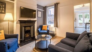 A living room with a fireplace, a television, a sofa, and a chair. - Ideal for Contractors | Free Wi-Fi | Sleeps 7! (Northampton)